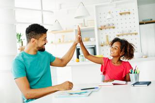 A male teacher gives a young female student a high five during a lesson